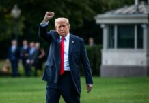 A political figure raising a fist while walking outdoors
