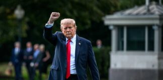 A political figure raising a fist while walking outdoors