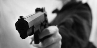 Close-up of a person holding a handgun in a threatening manner