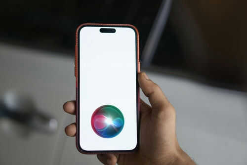 Hand holding smartphone with Siri logo visible