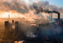 Kyiv’s Swarm Overwhelms Moscow Defenses Industrial facility with smoking chimneys under a colorful sky