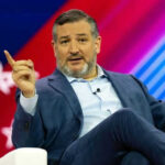 Cruz Explodes: Communist Or Campaign Stunt? Person speaking on stage with colorful background