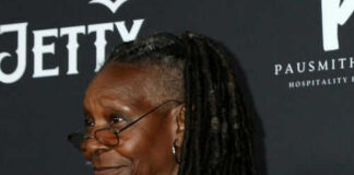 Person with dreadlocks smiling and wearing glasses.