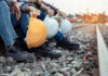 Railway workers sitting on track ballast holding hard hats