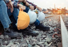 Big Pay, Short Gigs: AI’s Trade Trap Railway workers sitting on track ballast holding hard hats