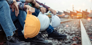 Railway workers sitting on track ballast holding hard hats