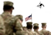 Tax-Free Troop Bonus Lands Before Christmas soldiers watch a drone fly near an american flag