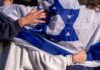 Ambassador Torches Khanna’s West Bank Tale People holding an Israeli flag together, showcasing unity and cultural pride