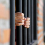 Espionage Playbook Snags American Scientist Hands gripping prison bars