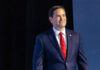 Rubio’s Terror Gambit Sparks Firestorm Man in suit and red tie on stage