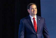 Rubio’s Terror Gambit Sparks Firestorm Man in suit and red tie on stage