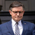 Speaker’s Stark Warning: Common Sense vs. Communism Man in blue suit with glasses looks down thoughtfully