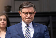 Speaker’s Stark Warning: Common Sense vs. Communism Man in blue suit with glasses looks down thoughtfully
