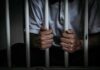 Reforms Agreed—Detentions Continue person gripping prison bars