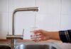 Drought Emergency Triggers Island Rationing Hand filling a glass with water from a kitchen faucet