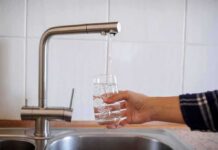 Drought Emergency Triggers Island Rationing Hand filling a glass with water from a kitchen faucet