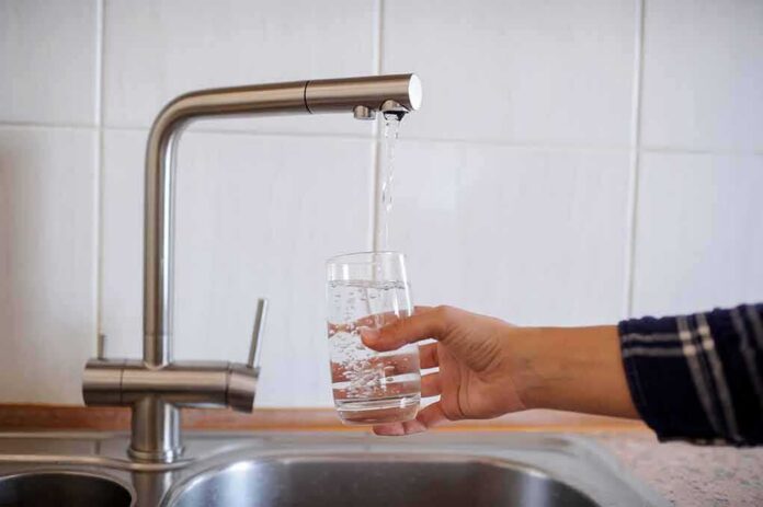 shutterstock_1128611180 Hand filling a glass with water from a kitchen faucet