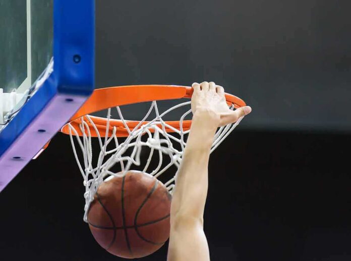 Basketball player dunks ball through orange rim