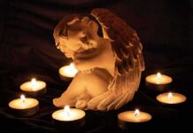 angel statue surrounded by lit candles