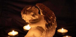 angel statue surrounded by lit candles