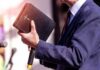 Pastors Vanish Overnight Across China A person in formal attire holding a Bible while speaking