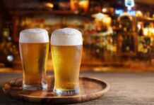 Woke Rebrand Backfires — Classic Label Returns Two glasses of beer on a wooden tray in a bar setting