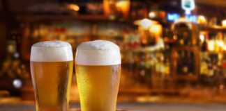 Two glasses of beer on a wooden tray in a bar setting
