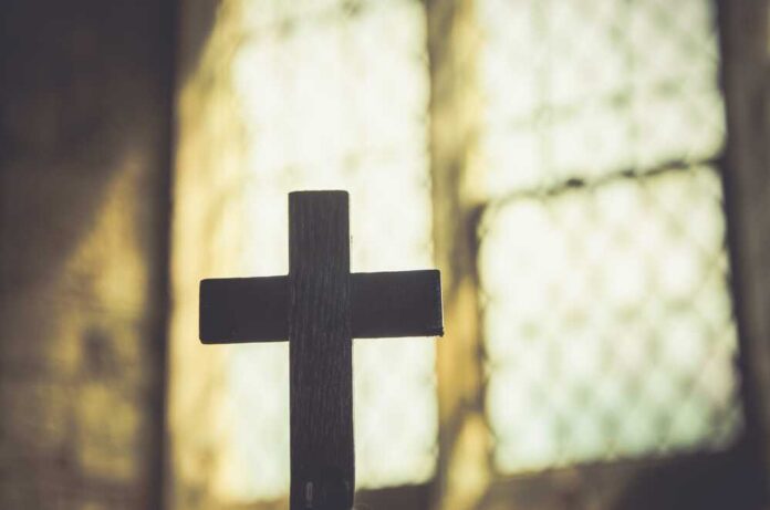 Silhouette of a wooden cross against a softly lit background