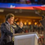 Deep State Showdown: Carlson Goes Rogue A speaker passionately addressing an audience from a podium