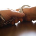 Dealer Flaunts Cash, Meets Chainsaw Justice Close-up of a handcuff being secured on a wrist
