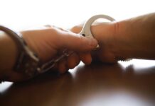 Dealer Flaunts Cash, Meets Chainsaw Justice Close-up of a handcuff being secured on a wrist