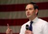Diplomacy With Teeth: Rubio Corners Tehran man speaking with microphone in front of an American flag
