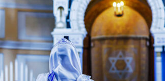 A person wearing a tallit in a synagogue during prayer