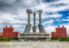 Nuke Boom Looms — Kim Goes Aggressive Monument with three raised stone hands holding hammer, sickle, and brush