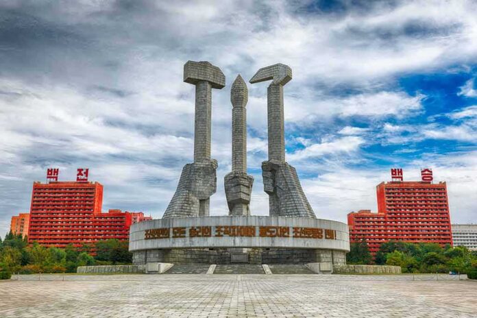 shutterstock_737133424 Monument with three raised stone hands holding hammer, sickle, and brush