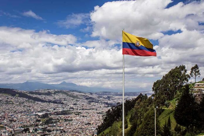 shutterstock_1104434312 Ecuador flag flying over a hillside city