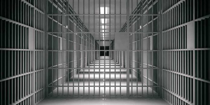 shutterstock_1118920109 empty prison corridor with barred cells