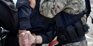 Officers detain a person with hands cuffed behind their back