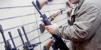 Person examining a black rifle in a gun store