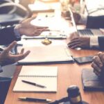 Education Dept Torpedoes ABA Stronghold Business meeting with hands gesturing over a conference table