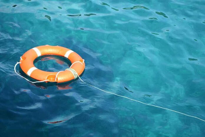 shutterstock_1252068862 Orange life buoy floating on blue water