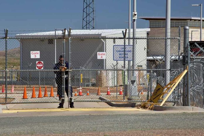 Security guard at chain-link gate of fenced facility