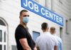 Man in face mask standing in line outside job center