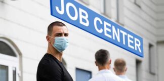 Man in face mask standing in line outside job center