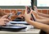 Algorithms Funnel Kids to Colombian Militias students' hands using smartphones at a classroom table