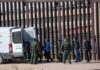 Court Smackdown Over Border Breakups Border agents escort a group near a tall fence and a patrol van