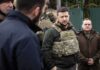 man in tactical vest stands with group outdoors