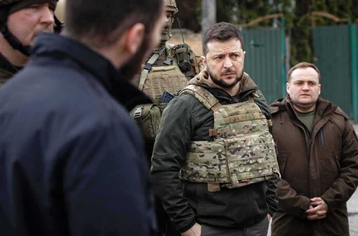 man in tactical vest stands with group outdoors