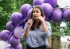 Egg-Freezing Drama Hijacks The Discourse Woman speaking into a microphone at an outdoor event with purple balloons