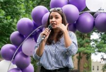 Egg-Freezing Drama Hijacks The Discourse Woman speaking into a microphone at an outdoor event with purple balloons